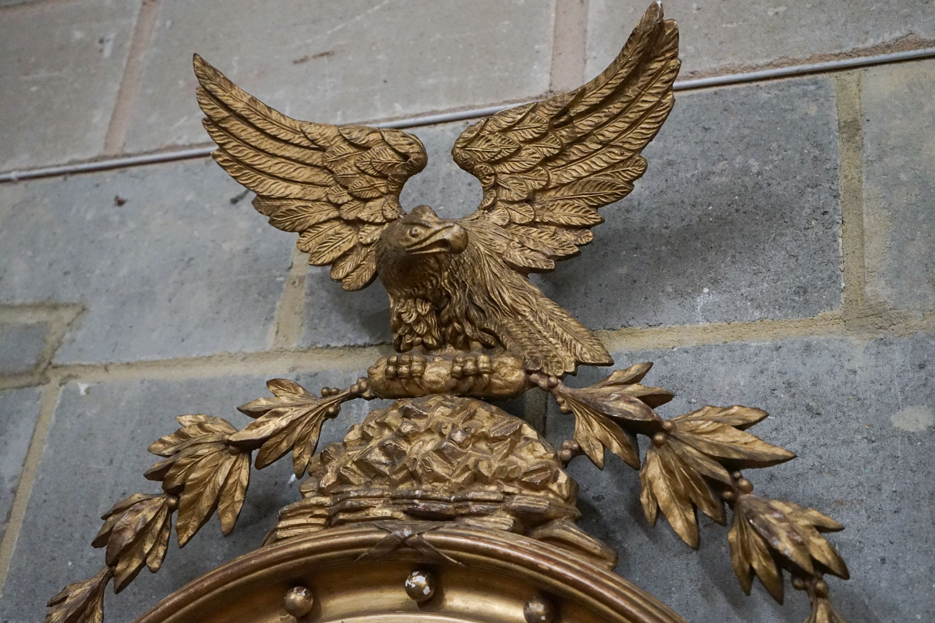 A Regency giltwood and gesso convex wall mirror with eagle pediment, width 60cm, height 94cm